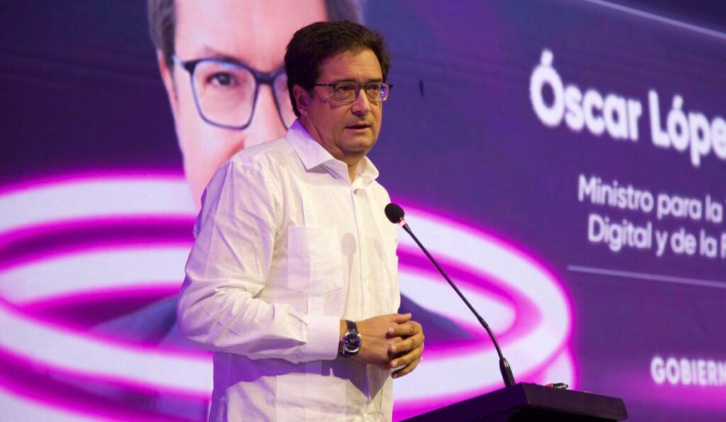 Hombre hablando en un podio con pantalla detrás.