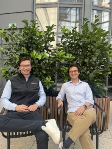Dos hombres sentados frente a plantas en un edificio.