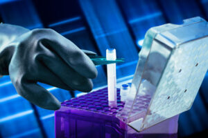 Mano con guante manipulando tubo de ensayo